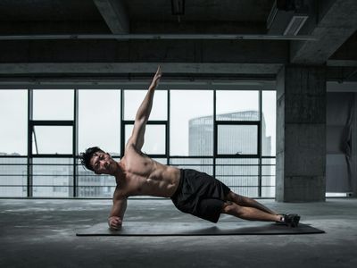 Strong man holding a plank position on a black mat.